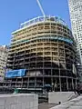 Uncladded shell of a building with 13 floors, with additional smaller floors being constructed above