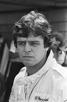 Derek Warwick in white racing outfit with his head to the right of the camera